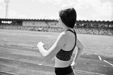 Portrait of a strong fit girl in sportswear running in the stadium. Black and white photo.