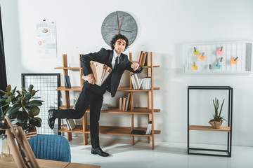 hurrying businessman with folders running in office not to miss deadline at work