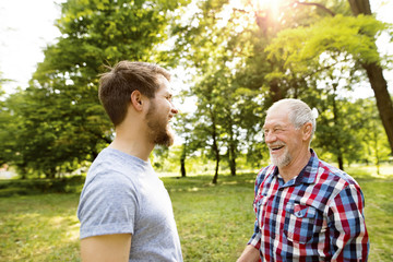 Senior father and his adult son laughing together in a park