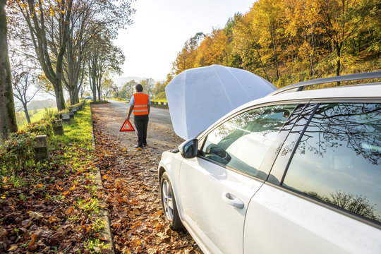 Back view of man with warning triangle having a car breakdown
