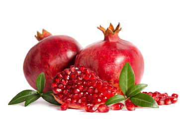 two whole and part of a pomegranate with pomegranate seeds and leaves isolated on white background