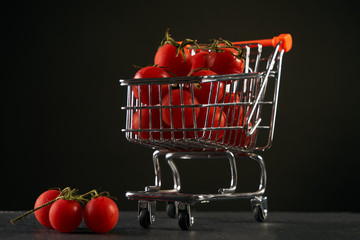 Fresh vegetables in shopping cart. Grocery shopping cart with vegetables fresh juicy tomato isolated on black background with copy space.