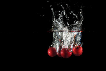 Cherries falling into water with splash