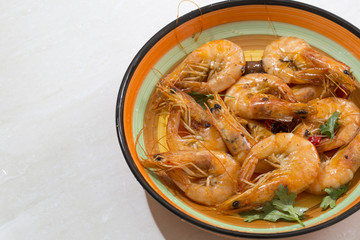 Delicious seafood shrimp with red pepper, coriander and olive oil made, and in a colorful  plate.