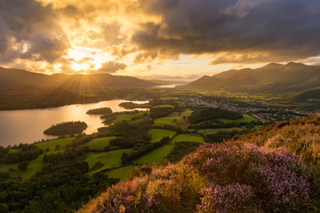 Sun setting behind moody clouds with dramatic evening light in the English Lake District.