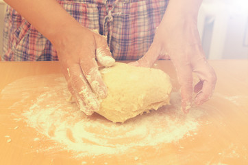 A woman kneads a homemade dough for pizza production.