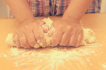 A woman kneads a homemade dough for pizza production.