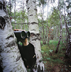 Man peeking from behind a tree in forest