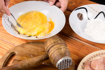 Mixing eggs in the plate with ingredients on the table