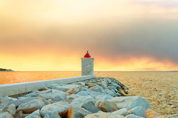 Naklejka premium Lighthouse in the harbor of a small town called Postira shot at sunset - Croatia, island Brac