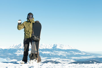 Fototapeta na wymiar Snowboarder holding blank lift pass in one hand and snowboard in another with beautiful mountains on background