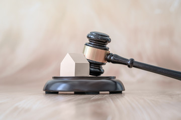 Judge's gavel and small house model over golden background. Close up. Living house auction