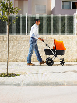 Father pushing pram on pavement