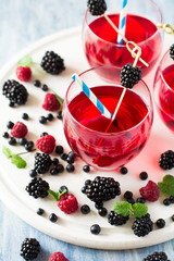 Fruit tea with blackberry, blueberry and raspberry decorated mint leaves on wooden desk. Selective focus