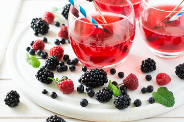 Fruit tea with blackberry, blueberry and raspberry decorated mint leaves on wooden desk. Selective focus