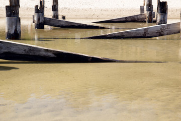 Fototapeta na wymiar Broken wooden structures on the sandy shore