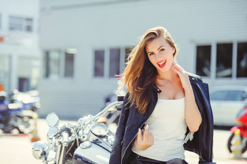 Fototapeta na wymiar Casual beautiful woman sits on a big tourist motorcycle on the street bright smile on a sunny day