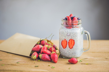Healthy layered dessert with chia pudding, strawberry and honeysuckle in a mason jar on rustic...