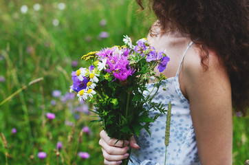 Naklejka premium Woman in cotton dress with bunch of summer flowers in the meadow