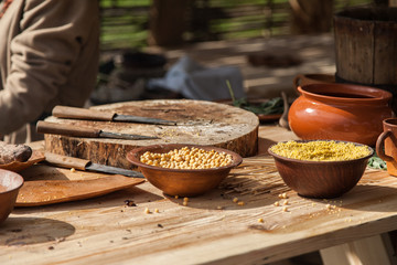 Chickpea and millet in the ceramic bowls on a wooden table among other kitchen utensils