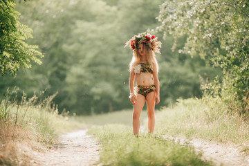 Beautiful little girl in image of nymph dryad stands in forest road. Close up. - obrazy, fototapety, plakaty