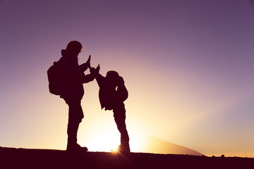 father and son with backpacks hiking at sunset