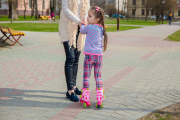 Mom and daughter ride on roller skates. Girl learning to roller skate, and falls. Mom teaches...