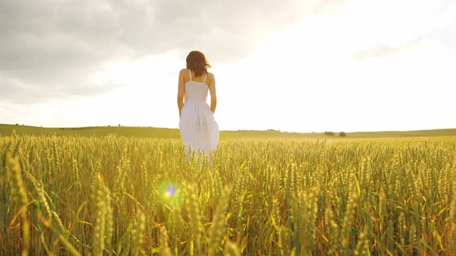 Young attractive woman in white dress enjoying the yellow field in the beatiful sunshine.