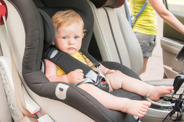Portrait of pretty toddler boy sitting in car seat. Child transportation safety