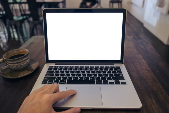 Mockup image of a man's hand using laptop with blank white screen on vintage wooden table in cafe