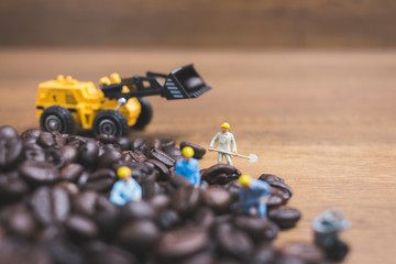 Miniature people working on roasted coffee beans