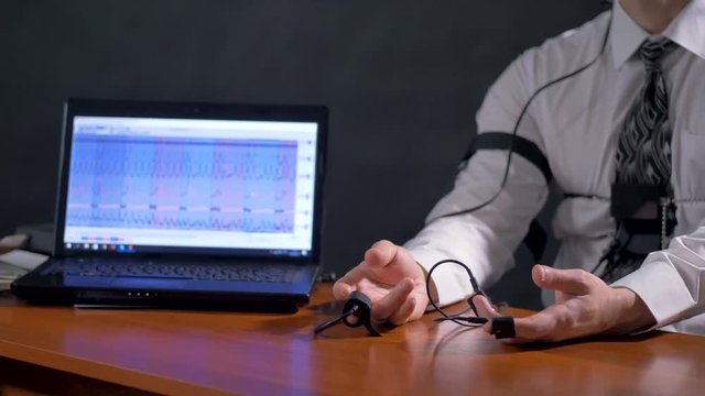 A lie detector test subject rests hands on a table. 