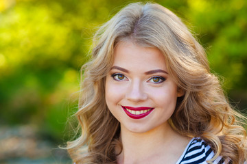 Naklejka premium Close portrait of a cheerful girl. Direct and cheerful girl hipster with elegant make-up in the summer outdoors.