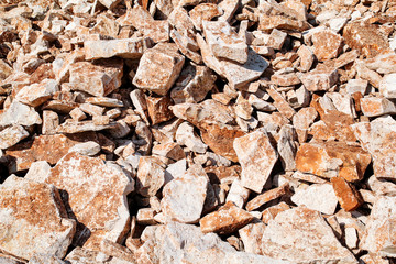 Fototapeta premium Part of a stone pile of rocks for construction and boulders piled, close up. Brown Granite. A large pile of limestone in quarry. Pile of gravel and construction material.
