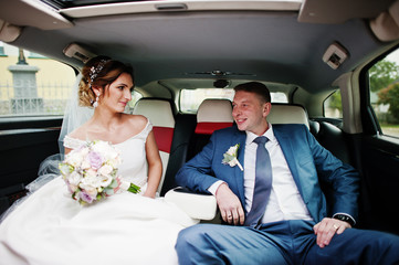 Fantastic wedding couple sitting in the limousine.