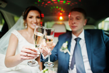 Newly married couple drinking champagne in the limousine on their wedding day.