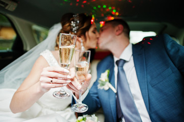Newly married couple drinking champagne in the limousine on their wedding day.