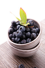 Juicy and fresh blueberries with green leaves on rustic table.