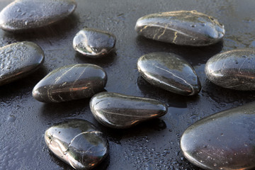 Stones for relaxation massage spa on a dark background with water drops