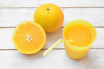 Fresh natural orange juice in a glass with a straw next to a sliced orange. Empty copy space for Editor's text.