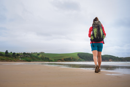 Backpacker girl traveler walk on deserted ocen beach