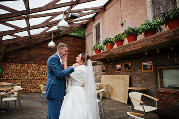Young married couple walking next to the old country house on their wedding day.