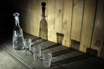 decanter and glasses with alcohol with shadows on a wooden background