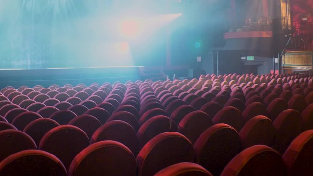 Stabilized camera movement from stage to armchair with beam of light highlighted by smoke 6