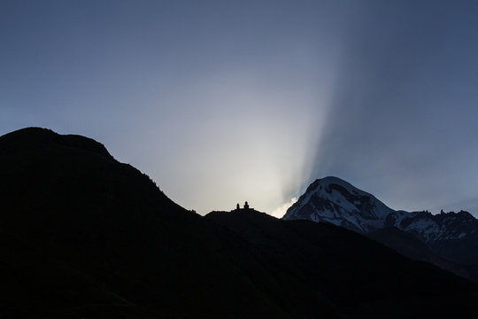 Church of the Holy Trinity on the mountain late in the evening during the sunset over Mount Kazbek in Georgia.
