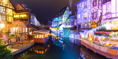 Panorama of traditional Alsatian half-timbered houses and river Lauch in Petite Venise or little Venice, old town of Colmar, decorated and illuminated at christmas time, Alsace, France - obrazy, fototapety, plakaty