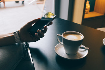Woman in a cafe using a mobile phone and drinking coffee