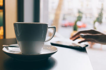 Woman in a restaurant drinking coffee and using a mobile phone