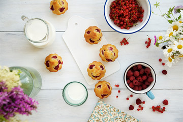 Wooden box with things for a picnic. Raspberry, muffins, milk, a notebook and wild flowers
