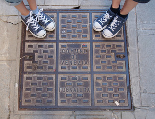 Pieds sur une plaque d'égout typique à Venise